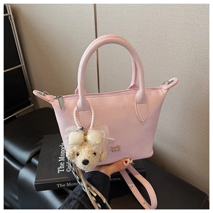 Détail du sac seau rose avec charm ours en peluche et logo de marque métallique