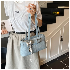 Detail of light blue denim texture shoulder bag with silver bow charm and buckle accent