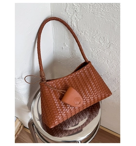 Close-up of the woven brown leather texture and elegant shoulder strap on a handbag