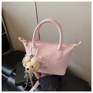 Détail du sac seau rose clair en cuir texturé avec un pendentif en peluche