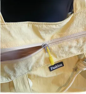 Detailed close-up of smooth zipper closure and black Fashion label on nylon tote bag