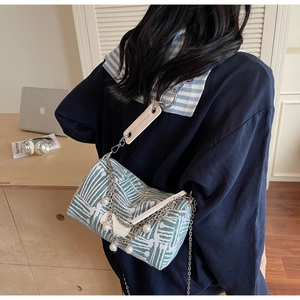 Detail of green canvas cylinder bag with pearl strap and gold chain crossbody strap