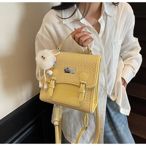 Détail du sac à main jaune tissé avec breloque de monstre blanc et boucles décoratives