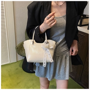 Detail of creamy white pleated bucket bag with pearl heart charm and lace ribbon