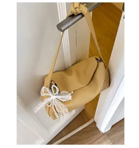 Detail of yellow dumpling bag with textured lychee leather and pearl lace bow charm