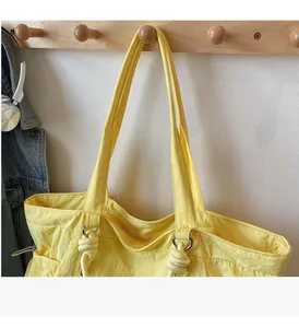 Detail of yellow nylon tote bag featuring durable handles and secure metal ring reinforcement