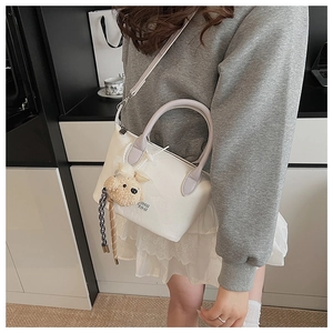 Détail du sac seau en cuir blanc cassé avec anse lilas et charmant ours en peluche