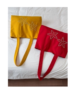 Detail of red and yellow canvas tote bags with handcrafted pearl star embroidery