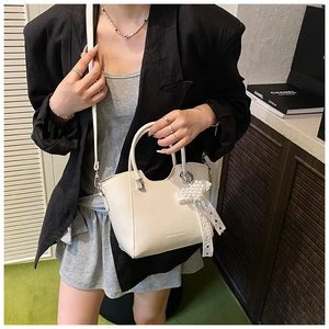 Detail of cream white bucket bag featuring grain texture and pearl bow charm