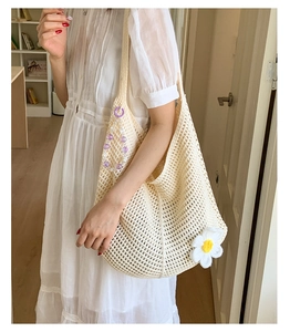 Nahaufnahme der beige Häkeltasche mit 3D Gänseblümchen-Akzenten und Perlenanhänger