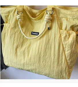 Detail of light yellow nylon tote bag featuring rope handles and Fashion woven label
