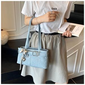 Detail view of light blue denim shoulder bag with metal buckle and silver heart charm