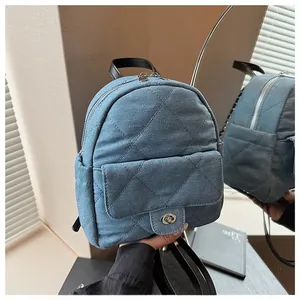 Detail of blue denim quilted mini backpack with silver twist lock and mirror reflection