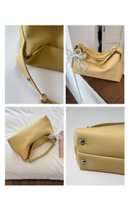 Detail view of yellow lychee grain leather handbag with lace bow and pearl charm