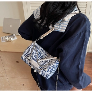 Detail of blue and white geometric canvas bag with chain and pearl fringe decoration