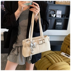 Detail of beige textured tote bag with silver bow heart pendant and buckle decor