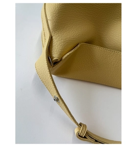 Close-up of yellow leather hobo bag showing silver metal buckle and neat stitching details