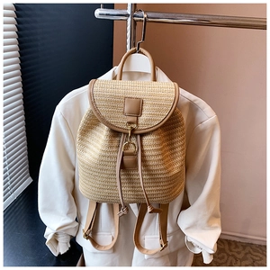 Dettaglio dello zaino in paglia intrecciata con patta in pelle e chiusura a coulisse