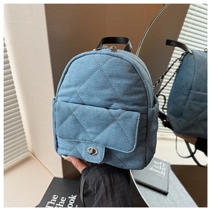 Close-up of quilted denim mini backpack with metallic twist lock and black leather trim