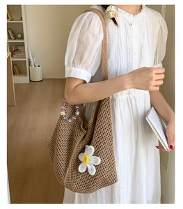 Detail der braunen Häkeltasche mit weißer Sonnenblume und lila Perlenkette