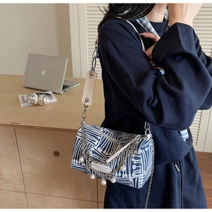 Detail showing blue and white woven canvas bag with silver chain and pearl pendant