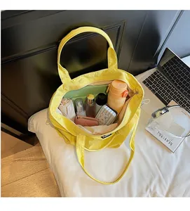 Internal capacity of large yellow nylon tote bag holding umbrella, bottle and wallet