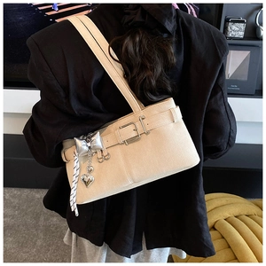 Detail of beige bucket bag with leather grain, heart pendant, and shoulder strap