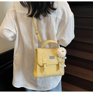 Vue arrière d'un mannequin portant un sac à dos jaune vif tressé avec un pompon blanc