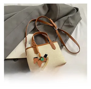 Detail view of contrast color bucket bag with horse charm on elegant grey coat