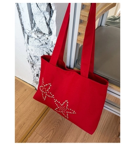 Detail of red canvas tote bag featuring silver metal star studs and sturdy top handles