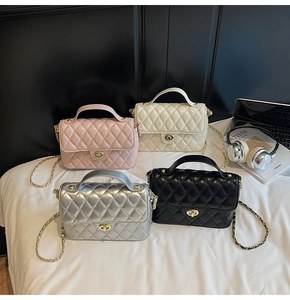 Quilted mini flap chain bags in pink, white, silver and black displayed on a bed