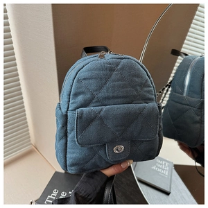 Close-up of a blue denim mini backpack with quilted diamond patterns and metal clasp