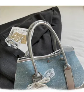 Detail of light blue denim bucket bag with sparkling crystals and pearl chain accessory