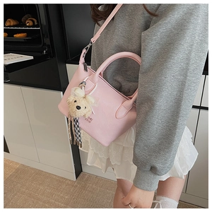 Détail d'un sac seau en cuir PU rose avec charm d'ours et bandoulière réglable pratique