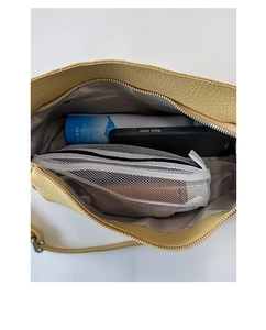 Top view of a pale yellow lychee leather bag interior with zipper and daily essentials
