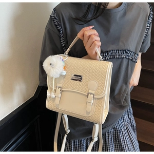 Détail du sac à main crème à texture tissée avec boucles et pendentif en peluche