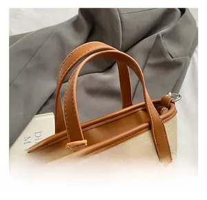 Detail of woven fabric tote bag with brown leather handles and premium stitching