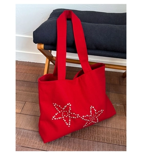 Close-up of red canvas tote bag featuring stylish silver metal rivet star patterns