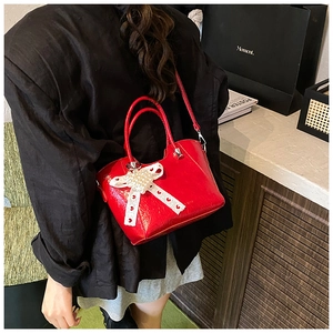 Detail of red patent leather bucket bag with lace bow and pearl heart decoration