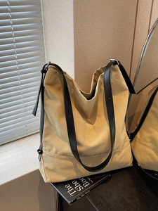 Minimalist khaki canvas bucket tote bag with black leather straps and silver buckle detail