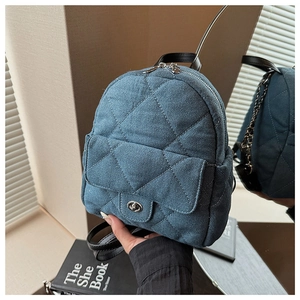 Detail of blue denim quilted backpack with silver twist lock and leather handle