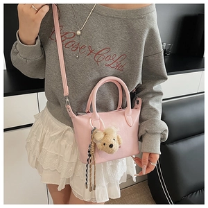 Détail du mini sac seau rose avec poignée en perles, charme d'ours et foulard rayé