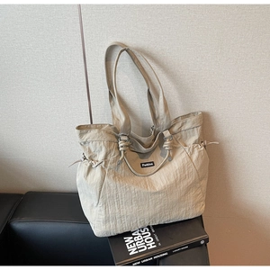 Detail of nylon tote bag featuring side drawstrings and a black Fashion label tag
