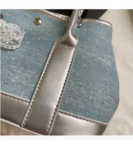 Close-up of light blue denim bucket bag featuring silver rivets and lace detailing
