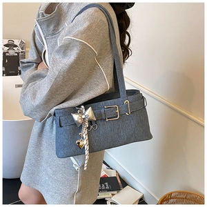 Detail of blue denim bucket bag with silver butterfly charm and heart pendant