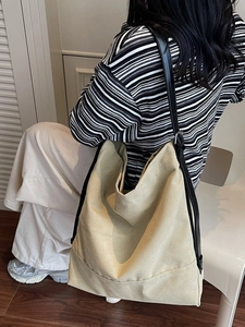 Large khaki canvas bucket tote bag with adjustable black leather straps for daily use
