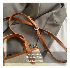 Detail of adjustable leather strap with silver metal buckle on canvas bucket bag