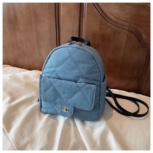 Macro detail of quilted denim texture and silver twist lock on mini backpack