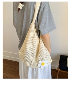 Detail einer beigen Stricktasche mit 3D-Gänseblümchen-Akzent und gewebtem Maschenmuster