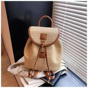 Detailed view of straw backpack with brown leather trim and metal hook closure